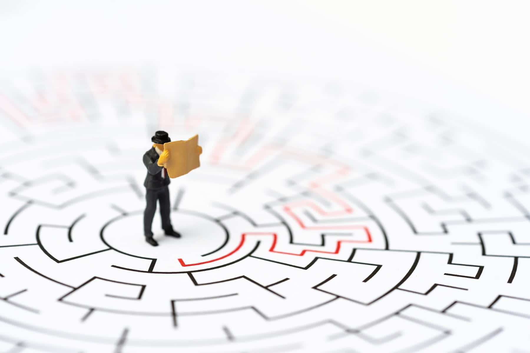 miniature people businessman labyrinth maze figuring out way out min